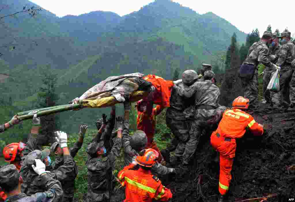Rescuers carry a victim&#39;s body in Taiping township in Lushan county of Yaan, southwest China&#39;s Sichuan province, Apr. 25, 2013. Tens of thousands of homeless survivors of the devastating quake are living in makeshift tents or on the streets.