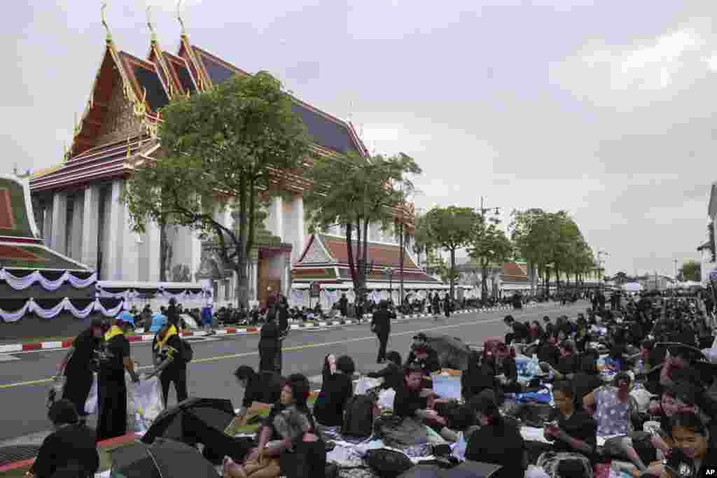 Thai mourners sit outside Wat Pho temple to take part in the royal cremation ceremony in Bangkok, Thailand, Wednesday, Oct. 25, 2017. (AP Photo/Wason Wanichakorn)