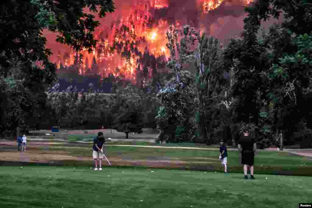 The Eagle Creek wildfire burns as golfers play at the Beacon Rock Golf Course in North Bonneville, Washington, U.S., Sept. 4, 2017.