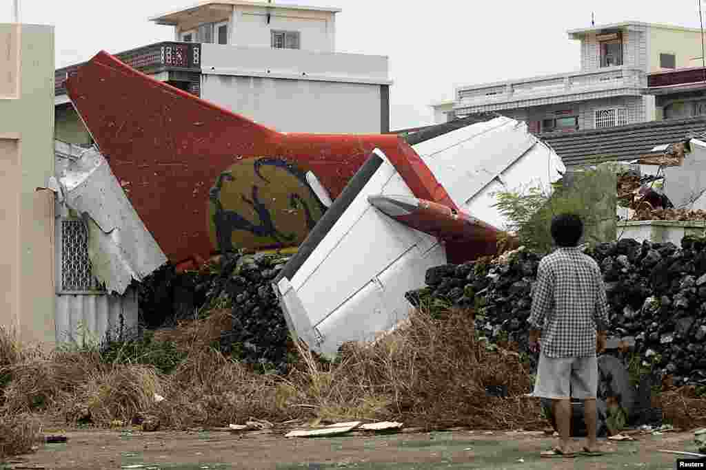 A man stands in his backyard and looks at the wreckage of a TransAsia Airways turboprop plane that crashed on Taiwan's offshore island Penghu.