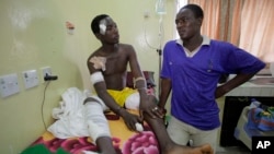 A victim of latest bomb explosion at a bus park gets a visit from his brother at the Asokoro hospital in Abuja, Nigeria, April 16, 2014.