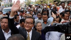 Sam Rainsy, front center, the head of the main opposition Cambodia National Rescue Party (CNRP) waves to the crowd before entering Phnom Penh Municipality Court in Phnom Penh, Cambodia, Tuesday, Jan. 14, 2014. Sam Rainsy and his party's Deputy President Kem Sokha appeared for questioning at the court about their possible involvement in inciting violence and social unrest, after four garment workers were brutality shot dead by government armed forces, on Jan. 3, according to a CNRP lawmaker. (AP Photo/Heng Sinith)