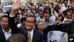 Sam Rainsy, front center, the head of the main opposition Cambodia National Rescue Party (CNRP) waves to the crowd before entering Phnom Penh Municipality Court in Phnom Penh, Cambodia, Tuesday, Jan. 14, 2014. Sam Rainsy and his party's Deputy President Kem Sokha appeared for questioning at the court about their possible involvement in inciting violence and social unrest, after four garment workers were brutality shot dead by government armed forces, on Jan. 3, according to a CNRP lawmaker. (AP Photo/Heng Sinith)