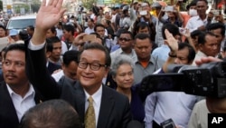 Sam Rainsy, front center, the head of the main opposition Cambodia National Rescue Party (CNRP) waves to the crowd before entering Phnom Penh Municipality Court in Phnom Penh, Cambodia, Tuesday, Jan. 14, 2014. Sam Rainsy and his party's Deputy President Kem Sokha appeared for questioning at the court about their possible involvement in inciting violence and social unrest, after four garment workers were brutality shot dead by government armed forces, on Jan. 3, according to a CNRP lawmaker. (AP Photo/Heng Sinith)