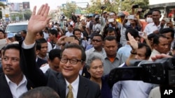 Sam Rainsy, front center, the head of the main opposition Cambodia National Rescue Party (CNRP) waves to the crowd before entering Phnom Penh Municipality Court, file photo. 