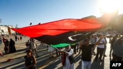 FILE - An elderly man waves a Libyan national flag during a demonstration in the Martyrs' Square in the centre of the Libyan capital Tripoli, currently held by the UN-recognised Government of National Accord (GNA), on June 21, 2020.
