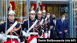 Presiden Prancis Emmanuel Macron, kanan, dan Menteri Kesehatan Prancis Olivier Veran, ketiga kanan, menunggu Direktur Jenderal WHO Tedros Adhanom Ghebreyesus saat mereka tiba untuk memimpin upacara pembukaan Akademi WHO di Lyon, Prancis tengah, 