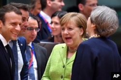 British Prime Minister Theresa May, right, speaks with from left, French President Emmanuel Macron, Luxembourg's Prime Minister Xavier Bettel and German Chancellor Angela Merkel before a round table meeting at an EU summit in Brussels, June 22, 2017.