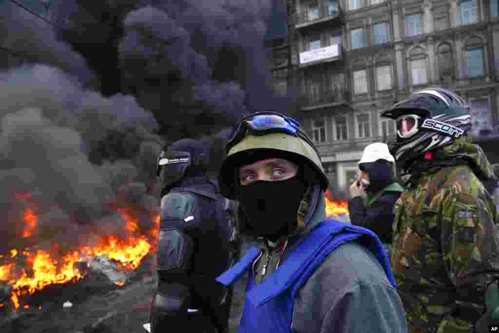 Protesters stand behind the barricade in front of riot police in central Kiev, Ukraine.