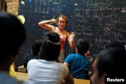 British volunteer primary school teacher Helen Brannigan holds a pen and a cup as she conducts an English class for refugee children at the volunteer-run "Refugee Education Chios" school on the island of Chios, Greece, Sept. 6, 2016.