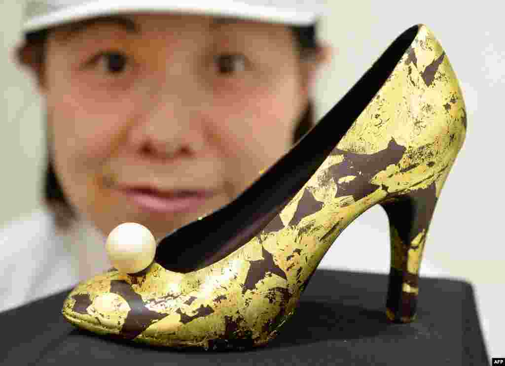 A salesclerk displays a high-heeled shoe-shaped chocolate decorated with gold leaves at the Seibu Department Store in Tokyo, Japan.