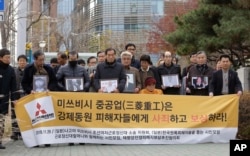 FILE- Victims of Japan's forced labor and their family members arrive at the Supreme Court in Seoul, South Korea, Nov. 29, 2018. The sign reads " Mitsubishi Heavy Industries apologize and compensate victims."