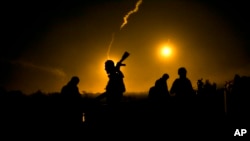 A U.S.-backed Syrian Democratic Forces (SDF) fighter watches illumination rounds light up Baghouz, Syria, March 12, 2019, as the last pocket of Islamic State militants is attacked. 