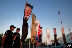 Turkish police provide security as posters with pictures of Prime Minister Binali Yildirim, left, and President Recep Tayyip Erdogan, background right, decorate the entrance to a mass Iftar dinner, the traditional meal to break the fast during Ramadan, organized by the ruling party, in Istanbul, June 25, 2016.