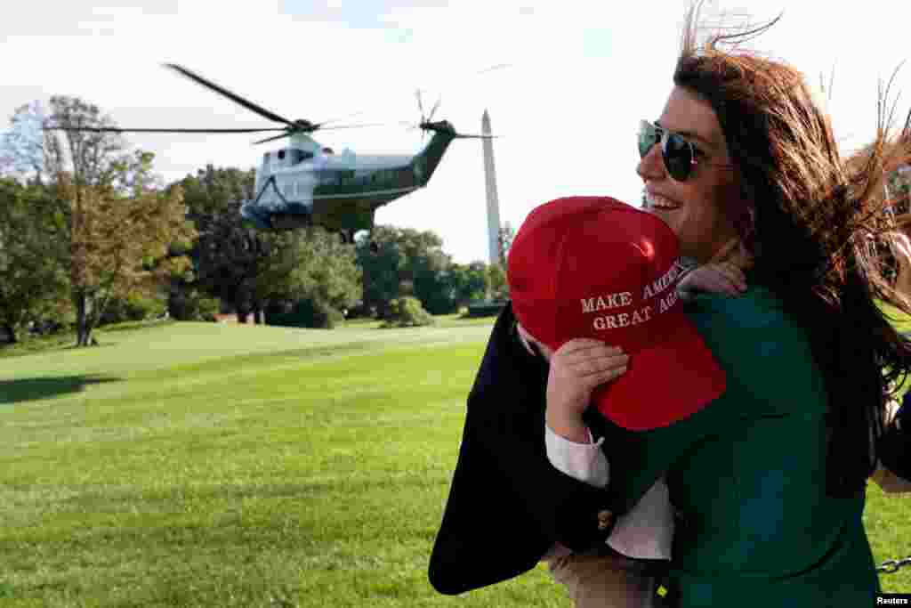 Megan Sanders and her son John, 4, react to wind as Marine One helicopter with U.S. President Donald Trump on board departs from the White House in Washington, Oct. 16, 2017.