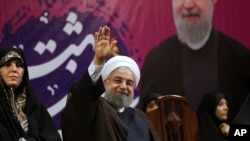 Iranian President Hassan Rouhani, center, waves to his supporters as he is accompanied by Vice President for Women and Family Affairs Shahindokht Molaverdi in a campaign rally for the May 19 presidential election in Tehran, Iran, May 9, 2017. 