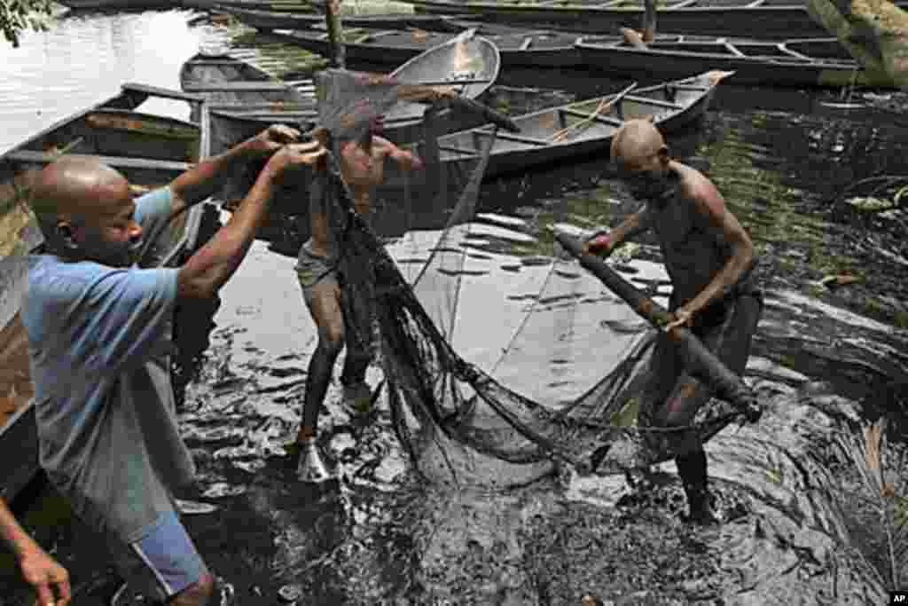 Fishermen sort out their fishing net at the bank of a polluted river in Bidere community in Ogoniland in Nigeria's delta region.