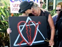 FILE - Leslie Gollub, left, and Gretchen Gordon hug at a vigil held to support the victims of a shooting at Chabad of Poway synagogue, in Poway, Calif., April 28, 2019.