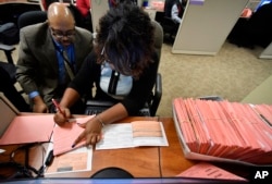 A Fulton County election worker counts provisional ballots in Atlanta, Nov. 7, 2018. Malfunctioning voting machines, missing power cords, and hours-long lines at the polls are being scrutinized in Georgia.