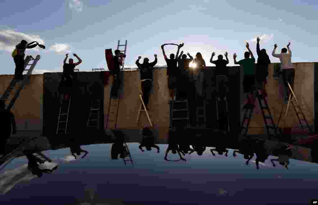 Fans, standing on ladders behind the fence, celebrate a goal as they watch a Czech first division match between Bohemians Prague and Zlin in Prague, Czech Republic.