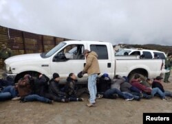 FILE - Border patrol agents detain suspects following an incident in which a truck smashed through the border wall in east San Diego, California, U.S., in this Feb. 21, 2019 handout photo. (CBP San Diego via social media)