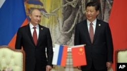 Russia's President Vladimir Putin and China's President Xi Jinping, right, smile during signing ceremony in Shanghai, China, on May 21, 2014.