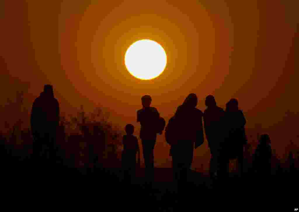 A family from a slum area walk home as the sun sets on the outskirts of Islamabad, Pakistan.