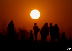 A family walk home as the sun sets on the outskirts of Islamabad, Pakistan, Sunday, Dec. 31, 2017.