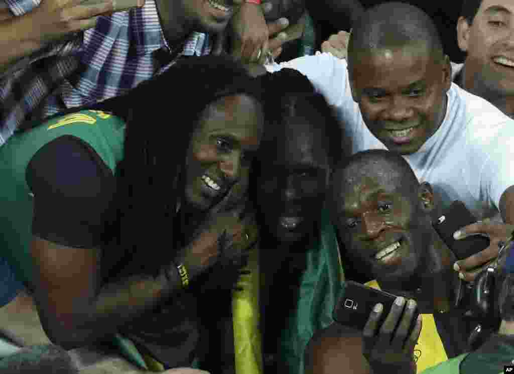 Le champion olympique jamaïcain se prend en selfies avec des supporters après sa victoire en finale de 100m messieurs, à Rio, brésil, 14 août 2016. 
