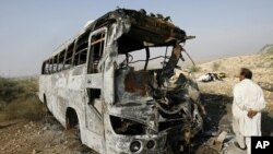 A man walks past the wreckage of a bus which was burned after it collided with an oil tanker in Nooriabad, in Pakistan's Sindh province 23 Jan 2011.