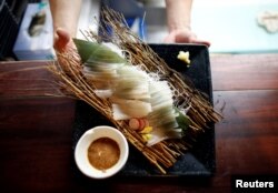 A chef serves flying squid sashimi at a seafood restaurant in Tokyo, Japan, Sept. 27, 2018.