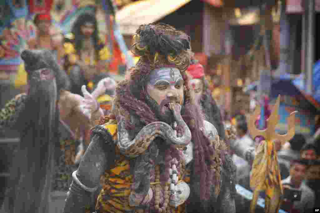 A devotee dressed as Lord Shiva puts a snake in his mouth during a procession to mark Mahashivratri festival in Prayagraj, Uttar Pradesh state, India.