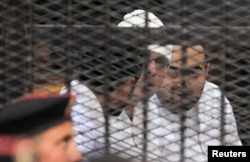 Political activists Ahmed Maher, Ahmed Douma (L) and Mohamed Adel (R) of the April 6 movement look on from behind bars in Abdeen court in Cairo, Egypt, Dec. 22, 2013.