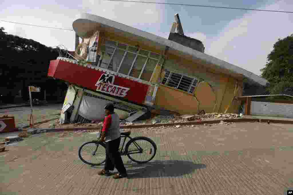 A man walks his bike past a building collapsed by a powerful earthquake, in Jojutla, Morelos state, Mexico, Sept. 20, 2017.
