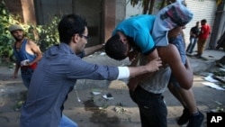 22일 이집트 수도 카이로에서 무르시 찬반 시위대가 충돌한 가운데, 반대 시위대들이 부상당한 동료를 옮기고 있다.
