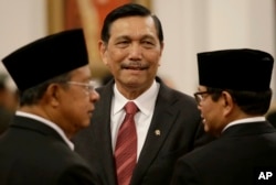Indonesia's Security Chief Luhut Panjaitan, center, talks with Cabinet Secretary Pramono Anung, right, and Coordinating Minister for the Economy Darmin Nasution, before the inauguration ceremony at Presidential Palace in Jakarta, Wednesday, Aug. 12, 2015.