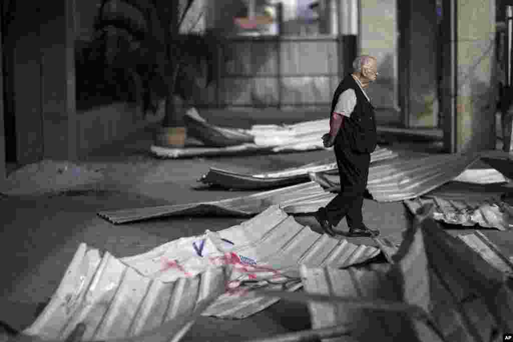 A man walks near the entrance of a commercial building that was damaged during protests in Rio de Janeiro, Brazil, June 21, 2013.