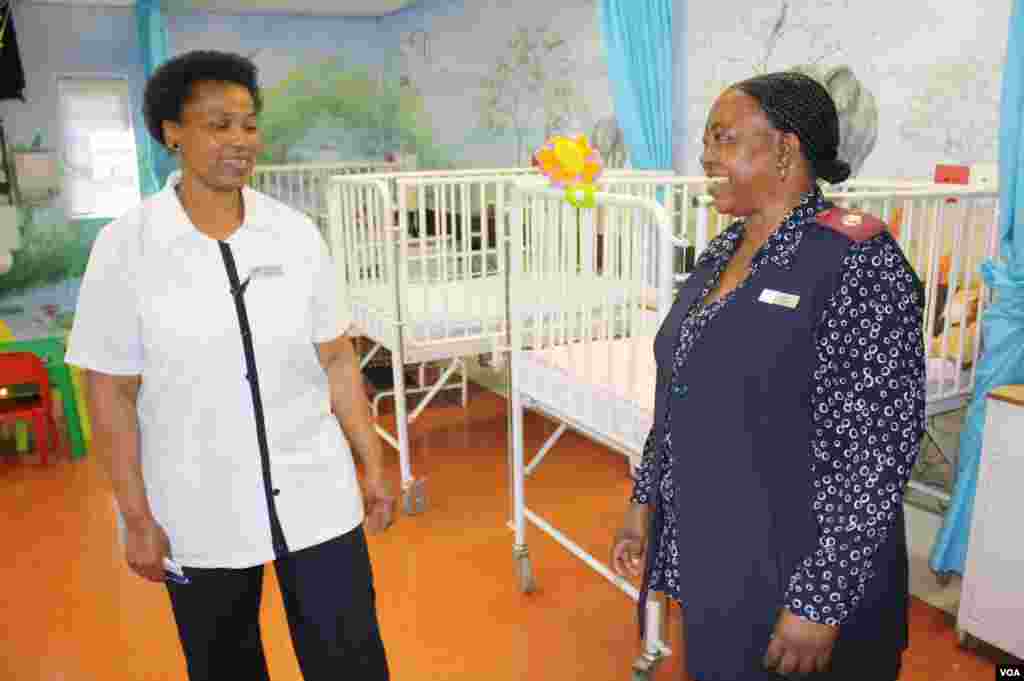 Nurses Duduzile Tlhapane (left) and Rachel Mabena meet inside a children’s ward in Soweto's Diepkloof Hospice. Tlhapane says she inspires her patients to “kick against death, even if your muscles are locked up tight.” (VOA/ D. Taylor)
