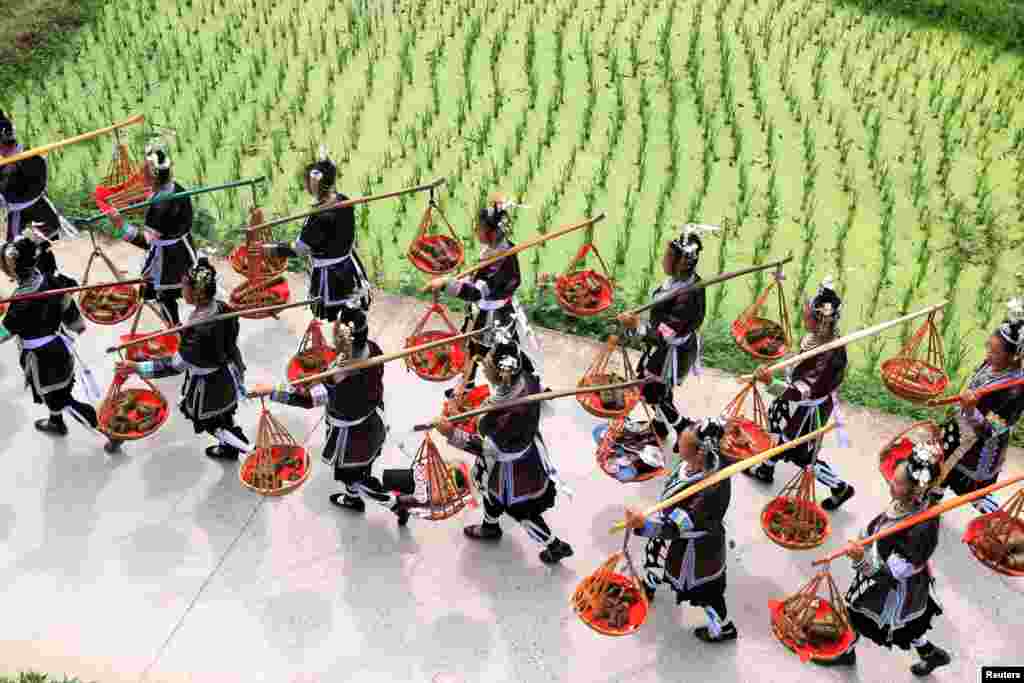 중국 구이저우성 리핑현의 소수계 동족 마을 전통축제에서 여성들이 찹쌀을 쪄서 만든 음식인 &#39;쫑쯔&#39;를 운반하고 있다.