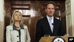 Secretary of State Hillary Rodham Clinton, left, listens to Treasury Secretary Tim Geithner, speak about new sanctions the U.S. is taking to increase pressure on Iran, at the State Department in Washington, Monday, Nov. 21, 2011.