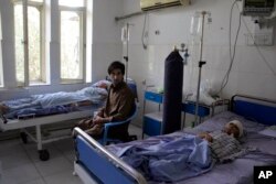 Un hombre y un niño reciben tratamiento en un hospital en la provincia de Kunduz, al norte de Kabul, el domingo 1 de septiembre, después de resultar heridos durante una lucha entre el Talibán y fuerzas de seguridad afganas el día anterior.