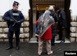 French police stand next to the entrance of Paris Mosque as French Muslims arrive for Friday prayers in Paris