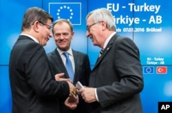 Turkish Prime Minister Ahmet Davutoglu, left, speaks with European Commission President Jean-Claude Juncker, right, and European Council President Donald Tusk, center, after a media conference at an EU summit in Brussels, Belgium, March 8, 2016.