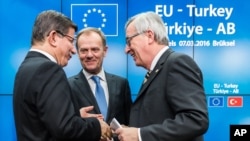 Turkish Prime Minister Ahmet Davutoglu, left, speaks with European Commission President Jean-Claude Juncker, right, and European Council President Donald Tusk, center, after a media conference at an EU summit in Brussels, Belgium, March 8, 2016. 