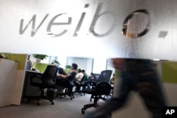 FILE - Employees work at their desks at a Sina Weibo office in Beijing.