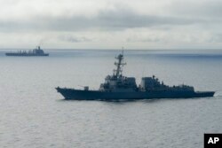 FILE - The USS William P. Lawrence guided missile destroyer, below, awaits refueling from a tanker, above, off Coronado, Calif., Jan. 20, 2016.