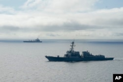 FILE - The USS William P. Lawrence guided missile destroyer, below, awaits refueling from a tanker, above, off Coronado, Calif., Jan. 20, 2016.