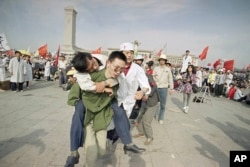 In this May 16, 1989 file photo, medics rush a Beijing university student from Tiananmen Square after he collapsed on the third day of a hunger strike in Beijing.