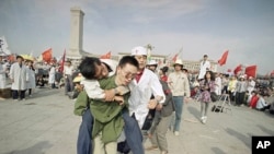 1989年5月16日，一名救护人员将一名绝食晕倒的北京大学生送出天安门广场。