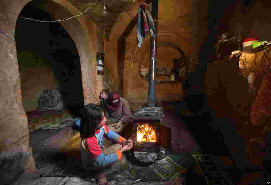Nihal, 9, puts olive tree branches inside a wooden stove at an underground Roman tomb which her family uses for shelter, Jabal al-Zaweya, Idlib province, Syria, Feb. 28, 2013.